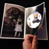 Photo of hand turning a page of the art booklet