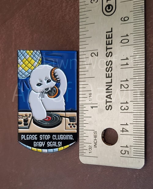 Photo of the Please Stop Clubbing, Baby Seals pin next to a ruler showing that it's height is 2 inches